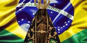 Imagem de Nossa Senhora da Conceição Aparecida com a bandeira do Brasil ao fundo.