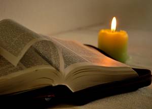 A Bíblia Sagrada iluminada por uma vela.