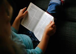Criança lendo a Bíblia Sagrada