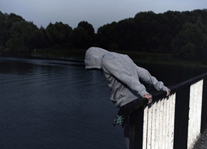 Homem jovem prestes a pular no rio - comportamento suicida.